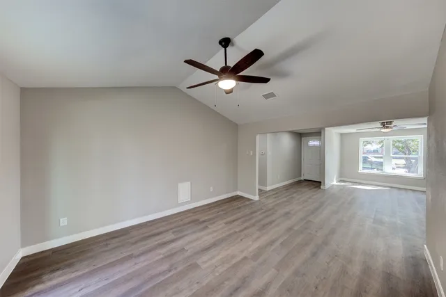 a view of an empty room with wooden floor and a window