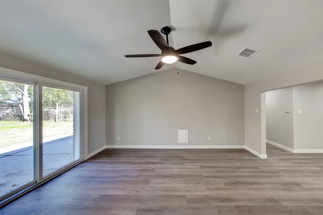 an empty room with wooden floor chandelier and windows
