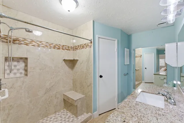 a bathroom with a granite countertop sink a toilet and shower