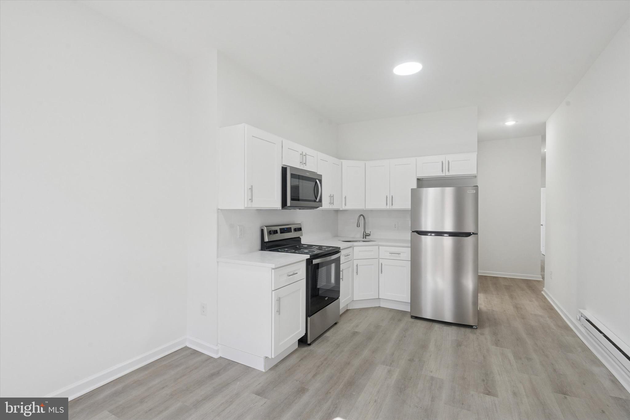 3827 Cambridge Street, Unit 1 Philadelphia, PA 19104 - Photo 7 of 7 a kitchen with stainless steel appliances a refrigerator and a stove top oven