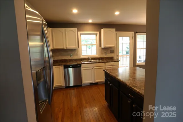 a kitchen with stainless steel appliances granite countertop a stove a sink a refrigerator and a microwave