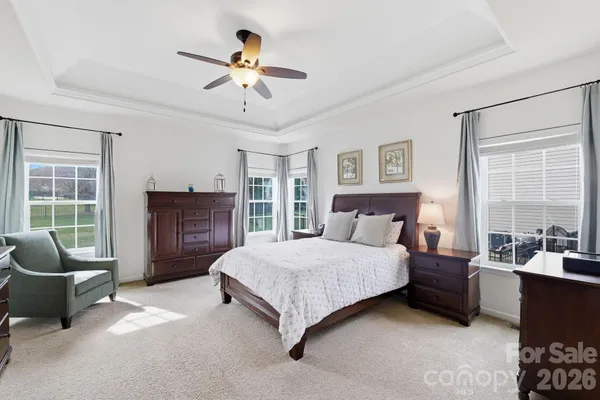 a spacious bedroom with a bed a couch and a chandelier