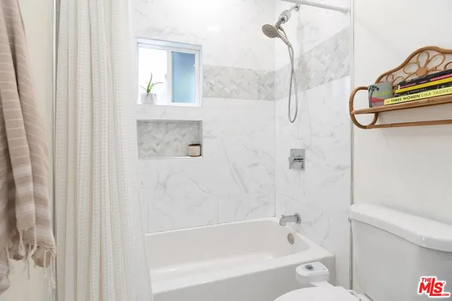 a bathroom with a bathtub a window and a shower