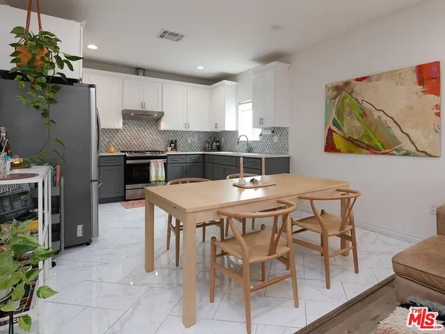 a kitchen with stainless steel appliances kitchen island granite countertop a table chairs stove and refrigerator