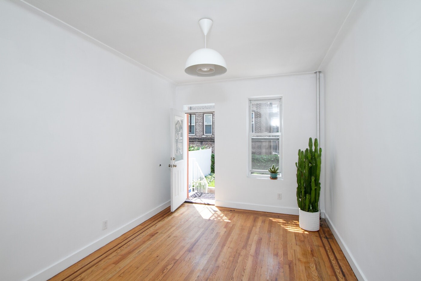 47-14 48th Street, Unit 1R Queens, NY 11377 - Photo 11 of 18 an empty room with wooden floor and windows