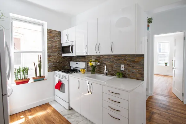 a kitchen with granite countertop a sink dishwasher a stove and a refrigerator with wooden floor