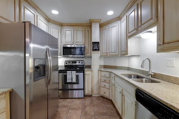 a kitchen with stainless steel appliances granite countertop a refrigerator stove and sink