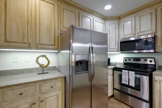 a kitchen with stainless steel appliances granite countertop a refrigerator a stove and a sink