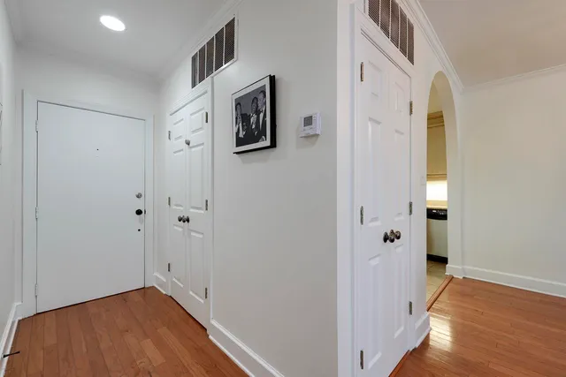 a view of a hallway with wooden floor and a bathroom