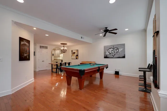 a living room with furniture pool table and a ceiling fan