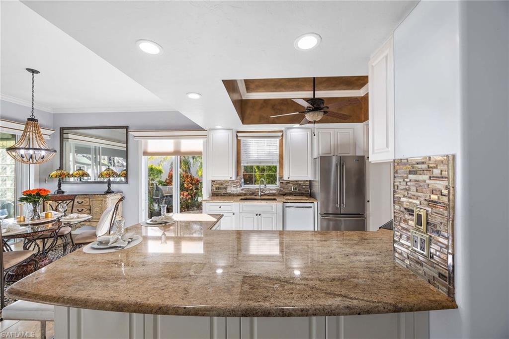 7534 Garibaldi Court Naples, FL 34114 - Photo 10 of 50 an open kitchen with granite countertop a stove and living room view