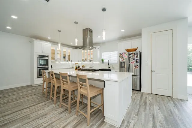 a kitchen with stainless steel appliances a dining table chairs and wooden floor