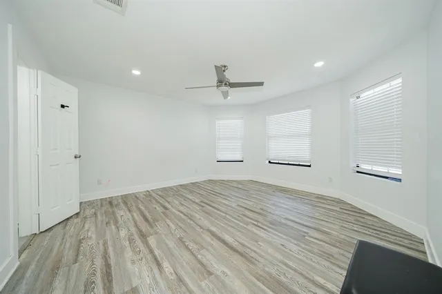 a view of empty room with wooden floor and fan