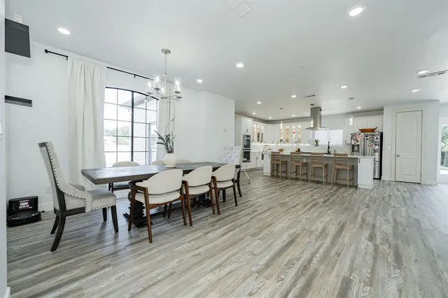 a living room with stainless steel appliances furniture wooden floor and a kitchen view
