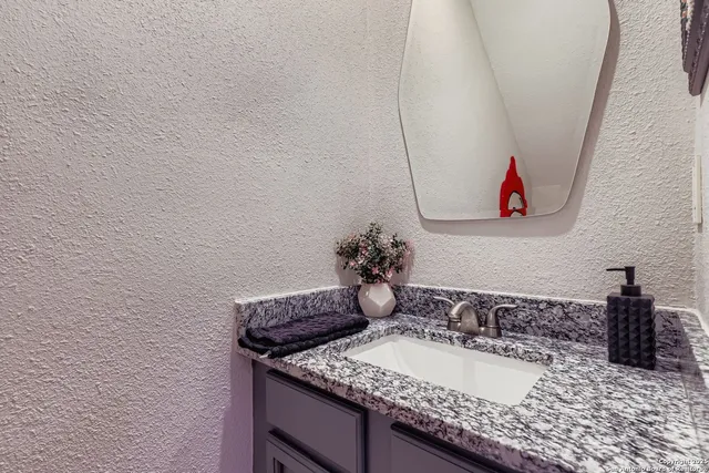 a bathroom with a granite countertop sink and a mirror