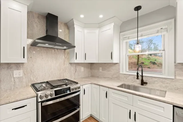 a kitchen with stainless steel appliances a stove a sink and white cabinets next to a window