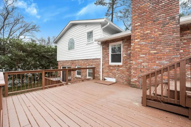a view of a balcony with wooden floor and bench next to trees
