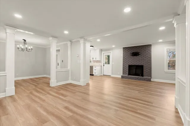 a view of an empty room with wooden floor and a kitchen