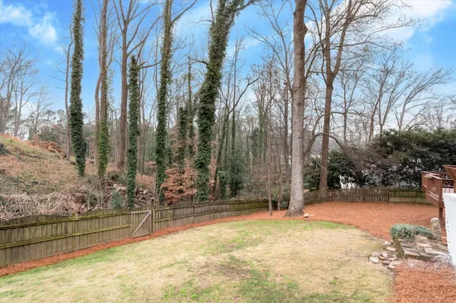 a view of house with yard outdoor seating and covered with trees