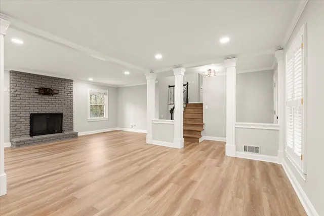 a view of an empty room with wooden floor fireplace and a window