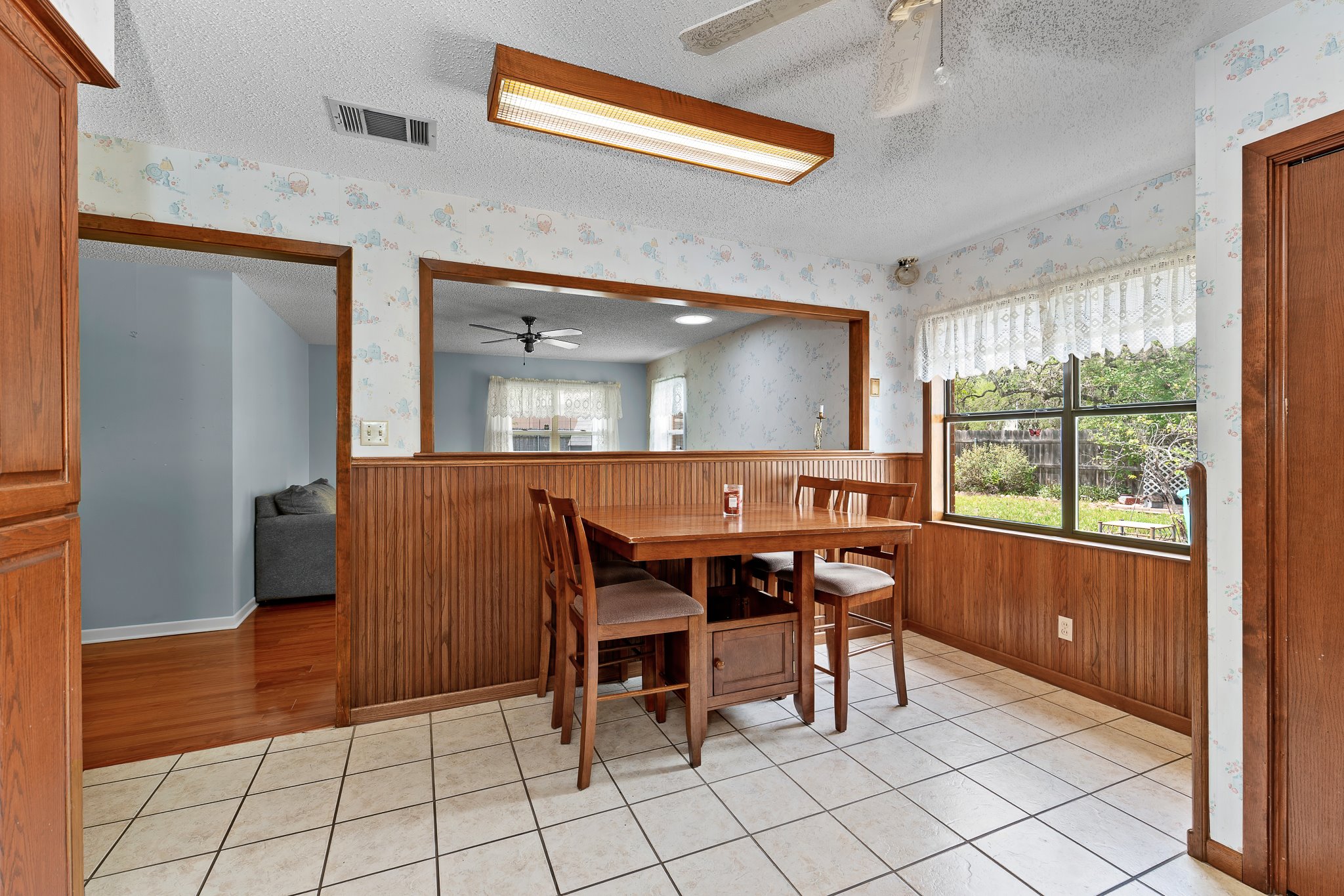 5600 Libyan Circle Austin, TX 78745 - Photo 11 of 37 Dining space with a textured ceiling, ceiling fan, wainscoting, wooden walls, and light tile patterned flooring