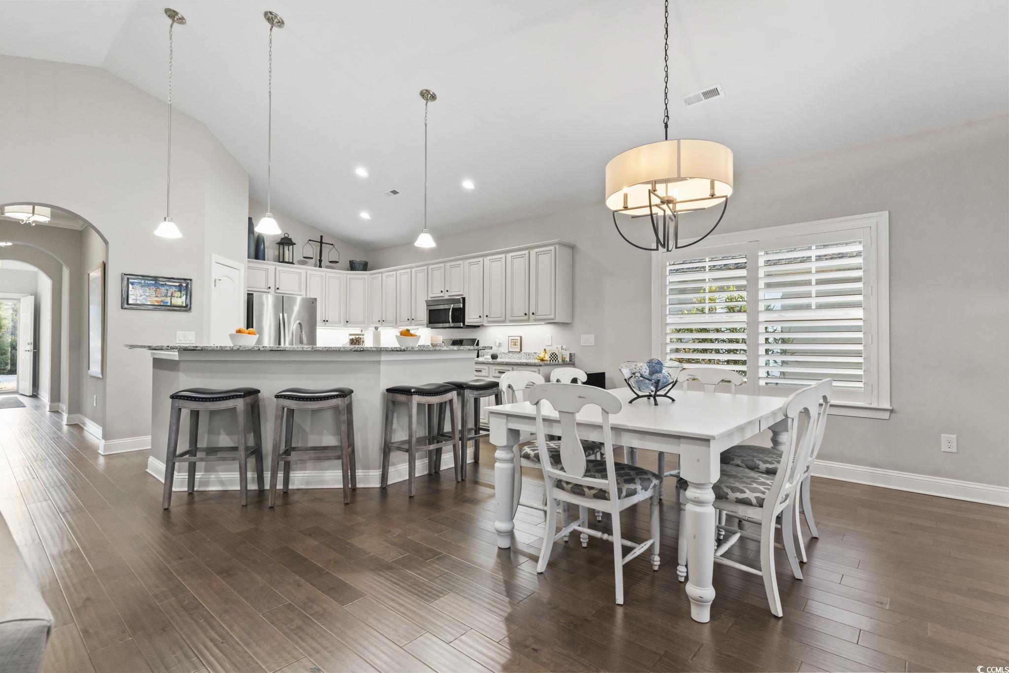 636 Elmwood Circle Murrells Inlet, SC 29576 - Photo 5 of 36 Dining area with arched walkways, high vaulted ceiling, plenty of natural light, and dark wood-style floors