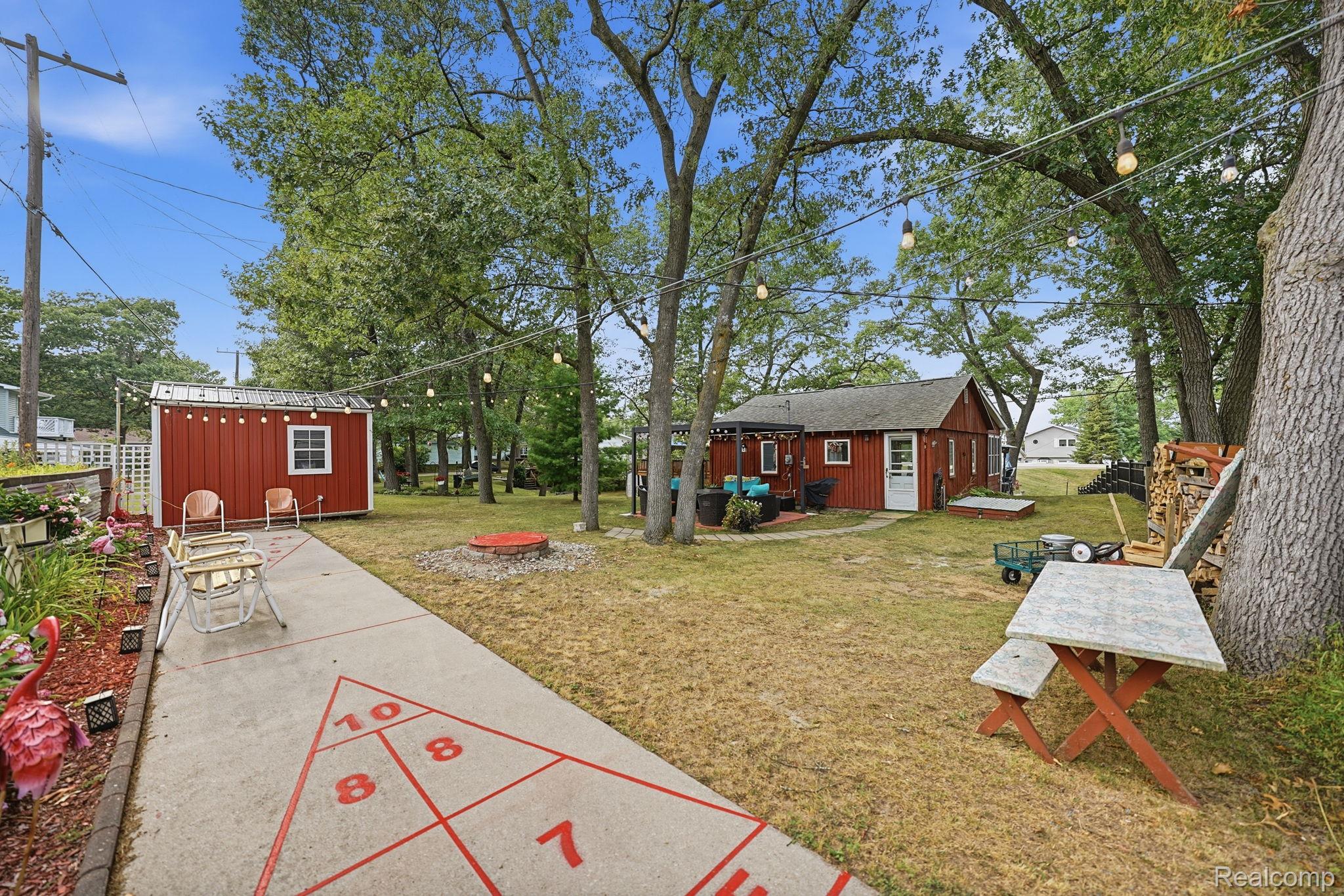 4599 Port Austin Road Caseville, MI 48725 - Photo 29 of 40 Expansive yard featuring a shuffleboard court, detached shed with a window, and a stone fire pit