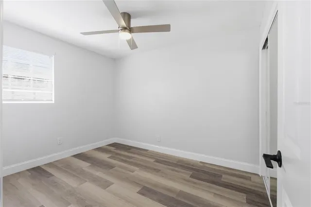 an empty room with a window and ceiling fan