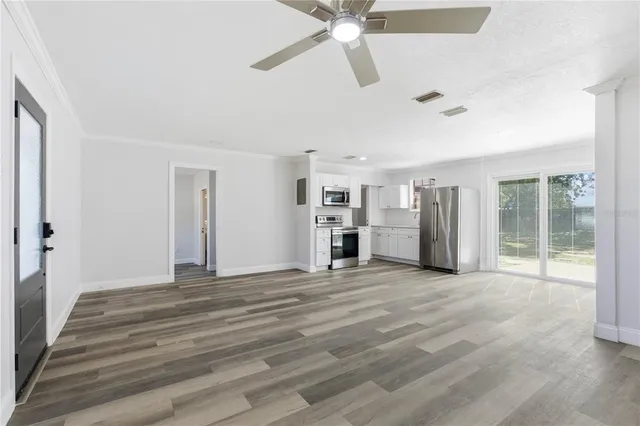 a view of an empty room with a window and a kitchen
