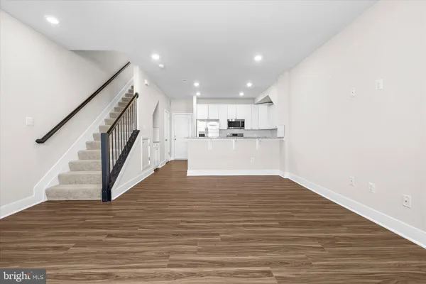 a view of kitchen with stainless steel appliances granite countertop a stove top oven a refrigerator with white cabinets and wooden floor