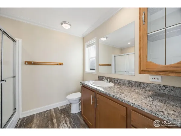 a bathroom with a granite countertop sink a toilet a mirror and shower
