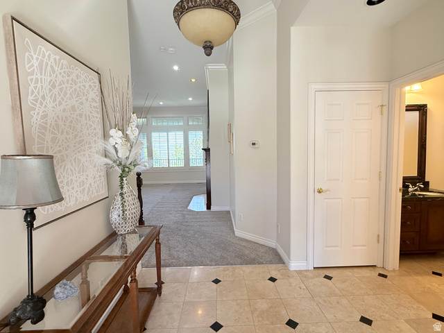 1562 Fairway Ridge Road Draper, UT 84020 - Photo 4 of 60 Entryway featuring light-toned tile flooring with dark accent squares, a decorative overhead light fixture, and crown molding