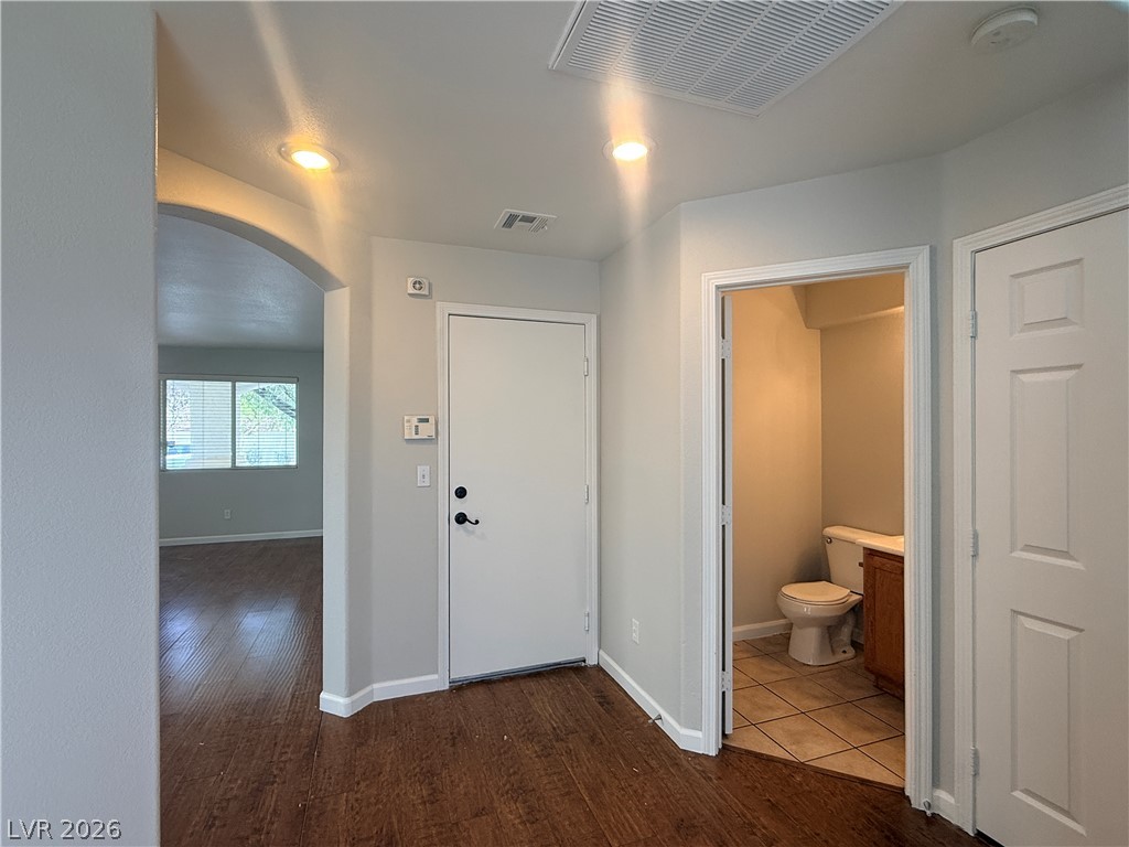 11953 Fairfax Ridge Street Las Vegas, NV 89183 - Photo 15 of 32 Rich hardwood flooring guides you through this home's inviting entryway, featuring a convenient half bath and an open arched doorway.