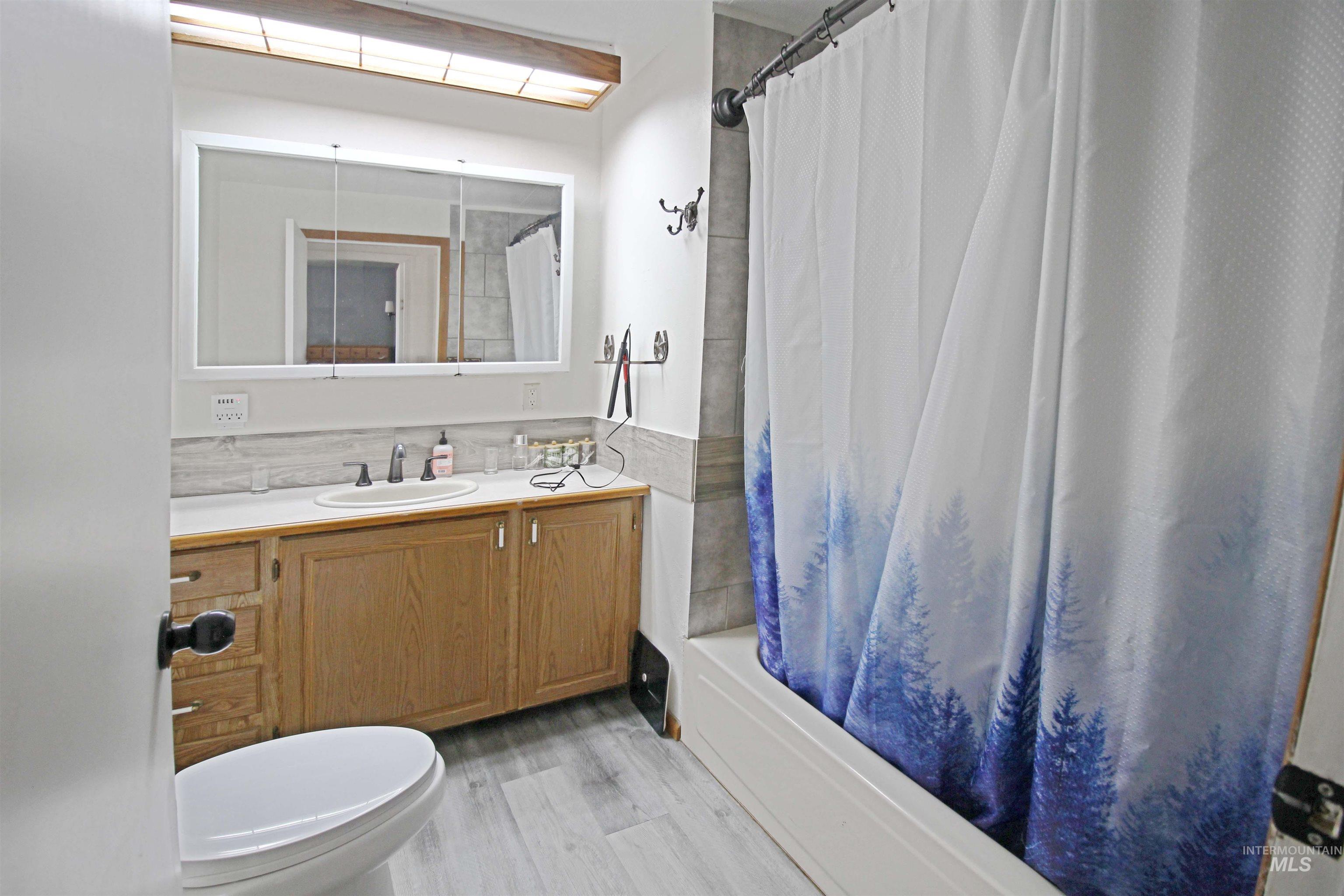 1265 Pioneer Road Weiser, ID 83672 - Photo 18 of 29 Bathroom featuring a single vanity with wood cabinetry, a built-in medicine cabinet, a full-size bathtub, and light-toned tile flooring