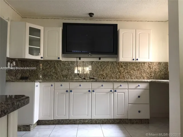 a kitchen with granite countertop white cabinets and sink