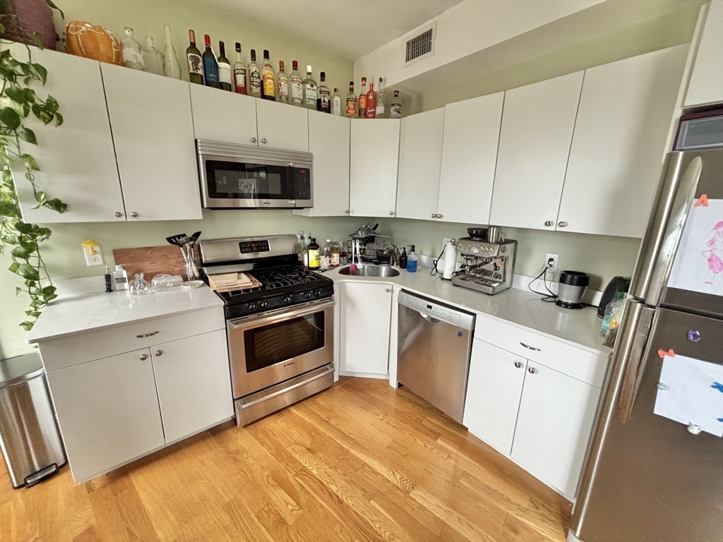 10 Roxbury Street, Unit 10 Boston, MA 02119 - Photo 1 of 8 a kitchen with stainless steel appliances a white stove top oven a sink and dishwasher