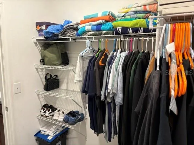 a view of walk in closet with clothes and shoes