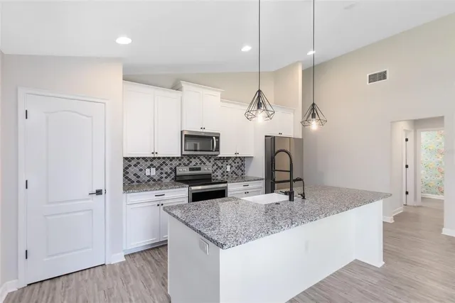 a kitchen with stainless steel appliances granite countertop a sink a stove and a wooden floor