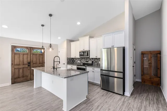 a kitchen with kitchen island a counter top space a refrigerator a sink and cabinets