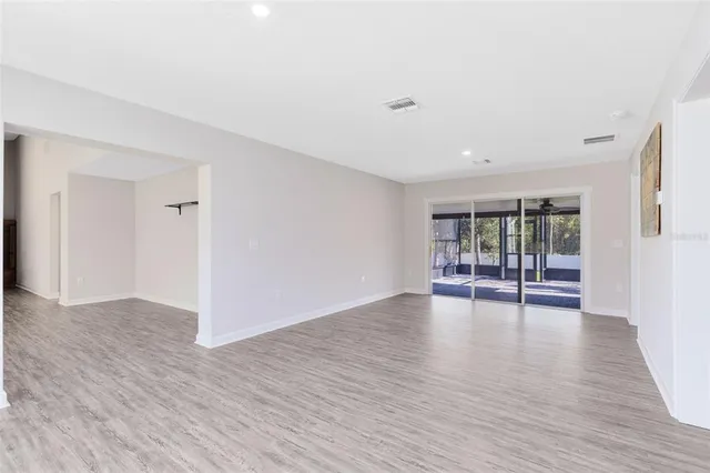 a view of empty room with wooden floor and floor to ceiling window