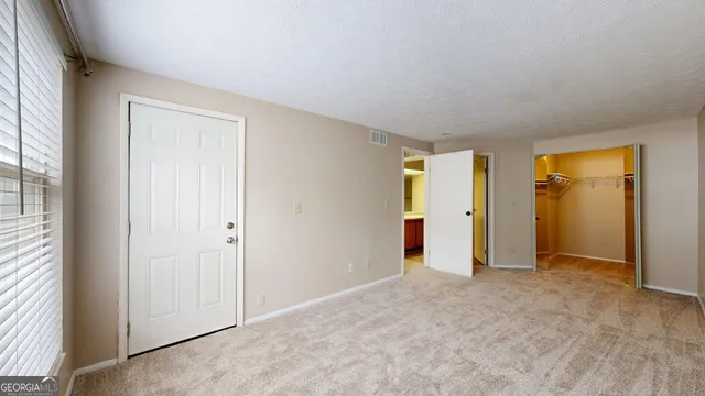 an empty room with window in back and closet area