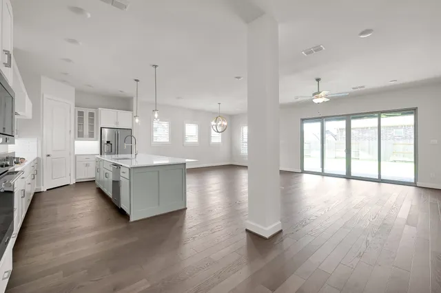 a large kitchen with kitchen island a stove a sink dishwasher and a oven with wooden floor