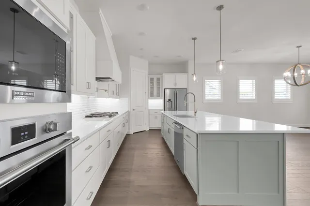 a kitchen with stainless steel appliances white cabinets a sink and a stove