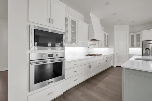 a kitchen with stainless steel appliances granite countertop a sink a stove and a wooden floors