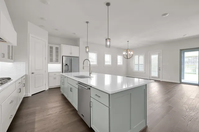 a large kitchen with stainless steel appliances a large counter top a sink a refrigerator and a window