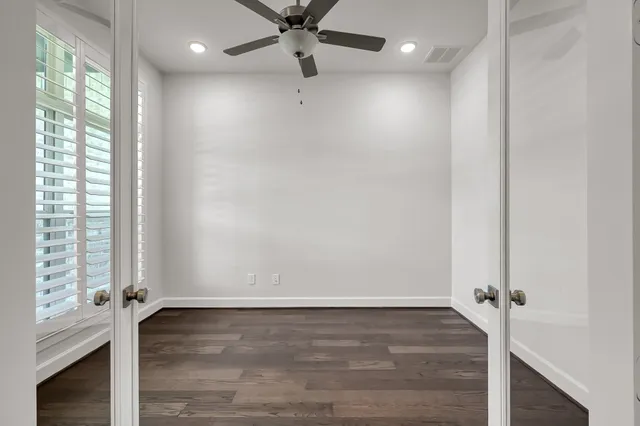 an empty room with wooden floor ceiling fan and windows