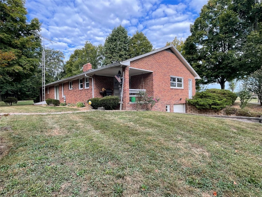 5990 Meese Road Northeast Louisville, OH 44641 - Photo 5 of 16 View of side of house featuring brick siding, an attached garage, a chimney, and a front lawn