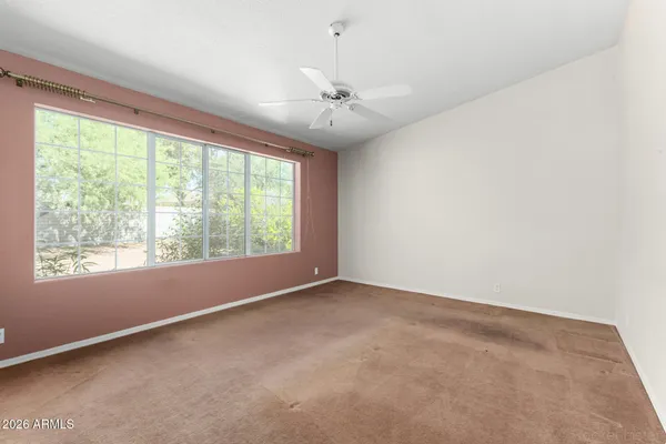an empty room with a chandelier fan and windows