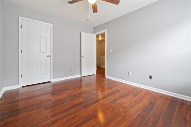 a view of an empty room with wooden floor a ceiling fan