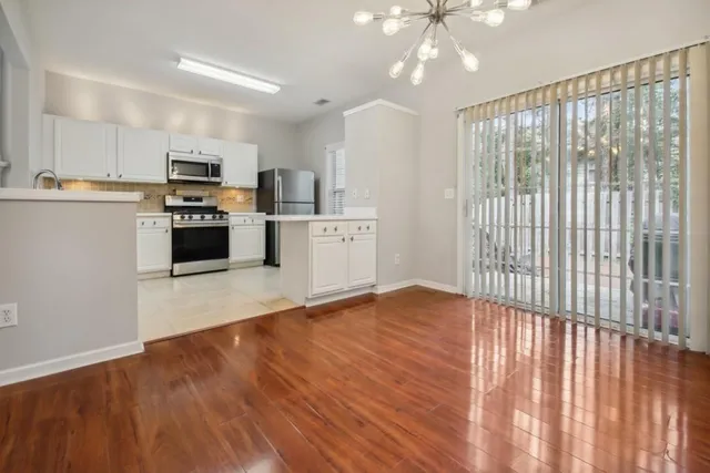 a kitchen with stainless steel appliances granite countertop a refrigerator oven a sink dishwasher and white cabinets with wooden floor